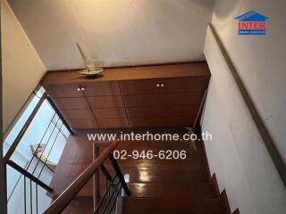 View of a wooden staircase with a cupboard under the stairs and a small decorative boat on top.