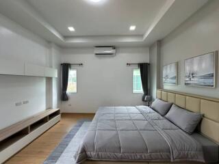 Modern bedroom with double bed, gray bedding, and wall-mounted air conditioner