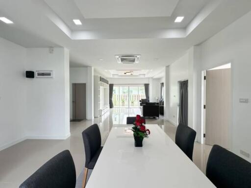 Spacious and modern open-plan living area with dining table and chairs, and access to a large balcony