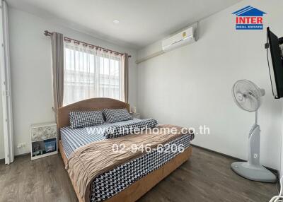 Well-lit bedroom with bed, fan, AC unit, and wall-mounted TV