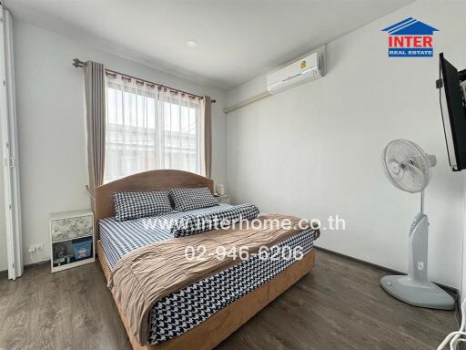 Well-lit bedroom with bed, fan, AC unit, and wall-mounted TV