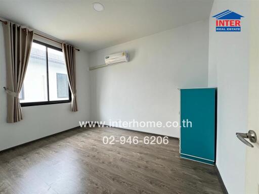 Empty bedroom with wooden floor, large window, air conditioner, and blue wardrobe