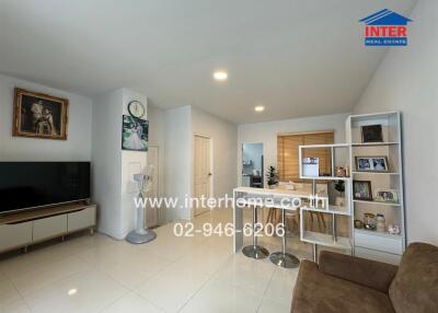 Modern living area with a TV, dining table, and shelves