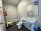 Modern bathroom with white tiled walls, a sink, toilet, and cat litter box