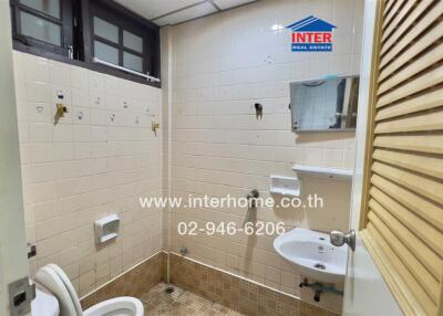 A basic bathroom with toilet, sink, mirror, and tiled walls