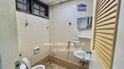 A basic bathroom with toilet, sink, mirror, and tiled walls