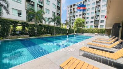 Outdoor swimming pool area with white and blue building in the background