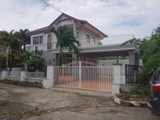 Exterior view of a two-story house with a gated entrance and a balcony