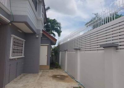 Backyard view of a modern house with gray exterior and a white fence