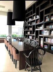 Dining room with large wooden table, chairs, and extensive book shelving