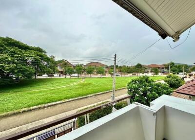 View from a balcony overlooking a grassy area and neighboring houses