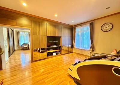 Spacious living room with wooden flooring, large TV, and ample natural light