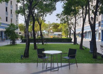 Outdoor communal area with greenery, tables, and chairs