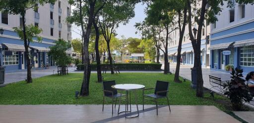 Outdoor communal area with greenery, tables, and chairs