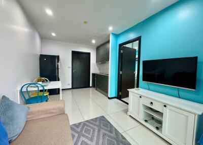 Modern living room with teal accent wall and kitchenette