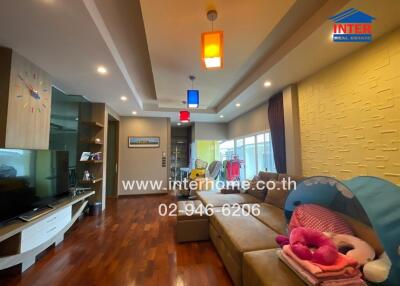 Spacious living room with wooden flooring, modern lighting, and a large sofa.