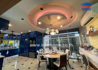 Modern dining area with circular ceiling design, adjacent to a kitchen