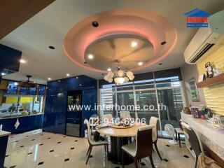 Modern dining area with circular ceiling design, adjacent to a kitchen