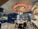 Modern dining area with circular ceiling design, adjacent to a kitchen