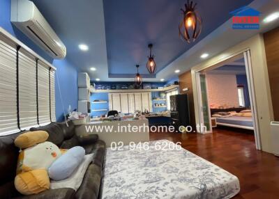 A cozy and spacious bedroom with a large bed, modern lighting fixtures, an air conditioner, a sofa, and access to another room