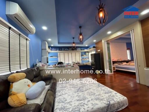 A cozy and spacious bedroom with a large bed, modern lighting fixtures, an air conditioner, a sofa, and access to another room