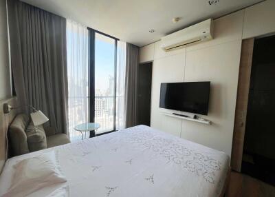 Modern bedroom with large window, air conditioner, wall-mounted TV, and wardrobe