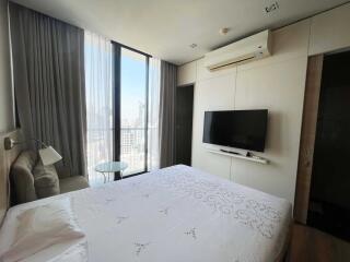 Modern bedroom with large window, air conditioner, wall-mounted TV, and wardrobe