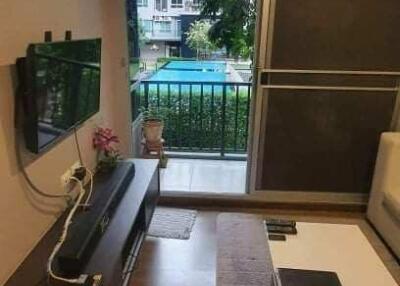 Living room with a modern interior design including a wall-mounted TV, coffee table, and a large window leading to a balcony with a view.