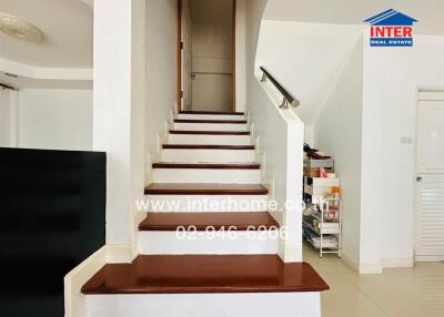 Modern staircase in residential building with white walls and dark wood steps