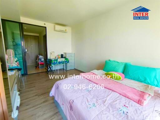 Bright and inviting bedroom with colorful bedding, air conditioning, and ample storage space