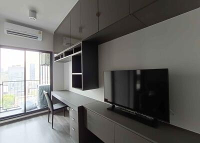 Modern living area with built-in storage and desk, adjacent to balcony