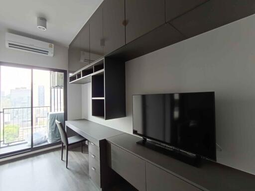 Modern living area with built-in storage and desk, adjacent to balcony