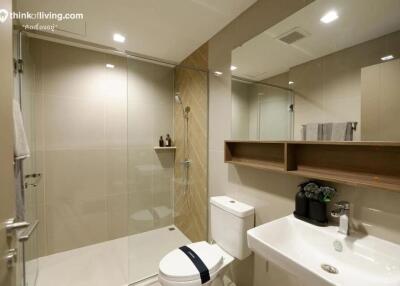 Modern bathroom with glass shower, white sink, and toilet