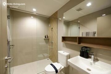 Modern bathroom with glass shower, white sink, and toilet