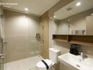 Modern bathroom with glass shower, white sink, and toilet