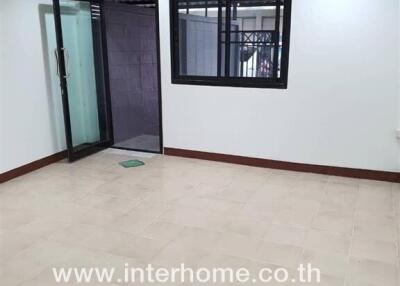 Bright empty room with tiled floors, large window, and glass door