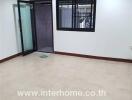 Bright empty room with tiled floors, large window, and glass door