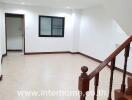 Spacious living room with tiled floors and wooden staircase