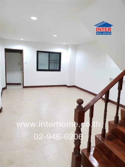 Spacious living room with tiled floors and wooden staircase