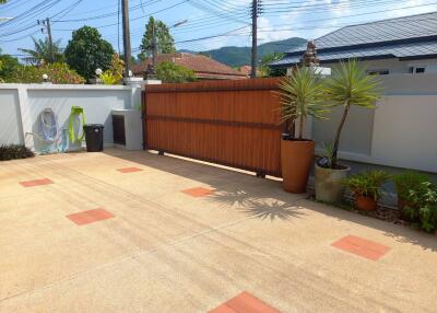Gated driveway with potted plants and garden hose holder