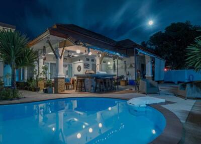 Night view of a house with poolside seating