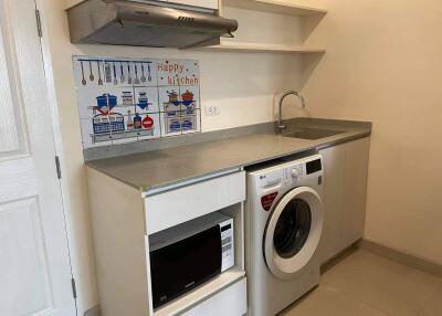 Modern kitchen with washing machine, microwave, and built-in shelves