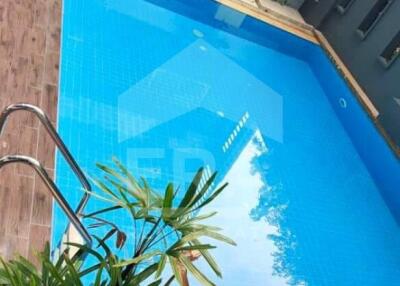 Outdoor swimming pool with wooden decking and surrounding greenery