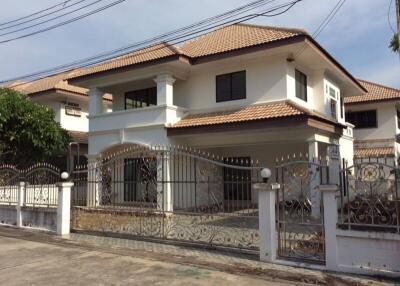 Two-story house with tiled roof and decorative wrought iron fence