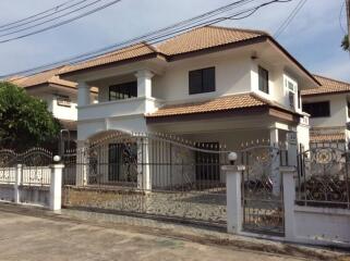 Two-story house with tiled roof and decorative wrought iron fence