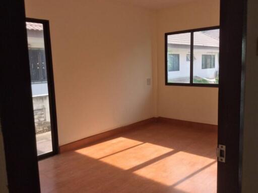 Empty bedroom with wooden floor and large windows