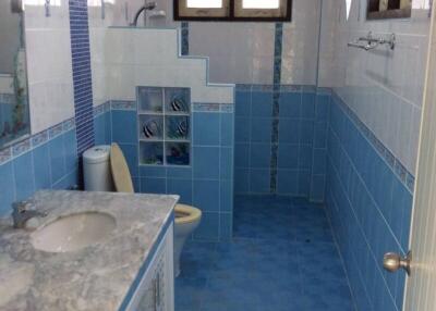 Modern bathroom with blue-tiled walls and floor, featuring a marble countertop sink and window for natural light.