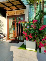 House entrance with glass door and flowering plants