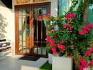 House entrance with glass door and flowering plants