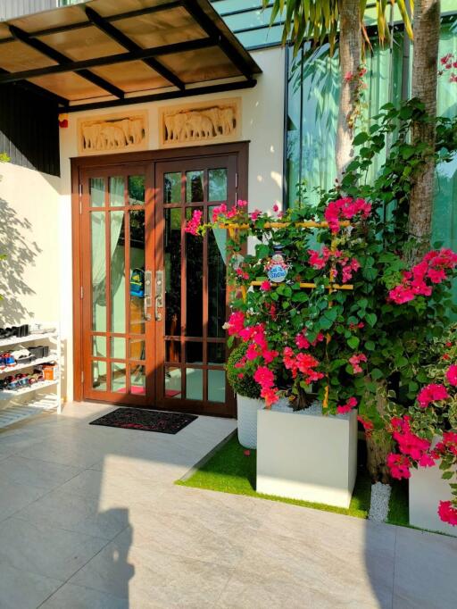 House entrance with glass door and flowering plants